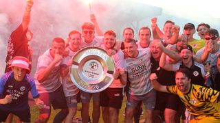 Eine Gruppe männlicher Athleten feiert das Halten eines Pokals. Sie alle lächeln und halten einen Pokal mit dem Wort Meister. Einige tragen Sonnenbrillen und einer hält eine Fackel. Der Hintergrund ist verschwommen mit rosa Rauch.