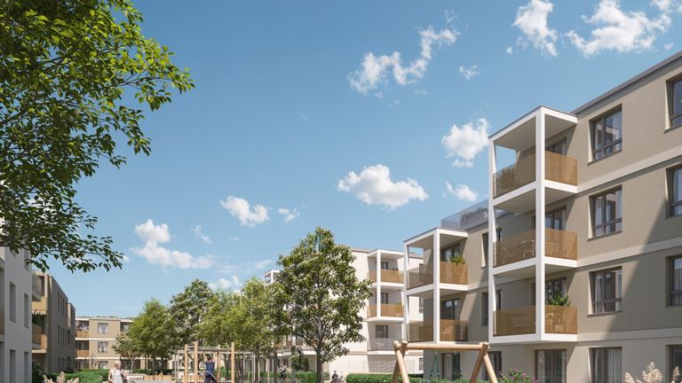 Ein modernes Wohnkomplex mit mehreren Wohnhäusern, Balkonen und einem Spielplatz unter einem blauen Himmel mit Wolken. Bäume sind um die Gebäude gepflanzt.