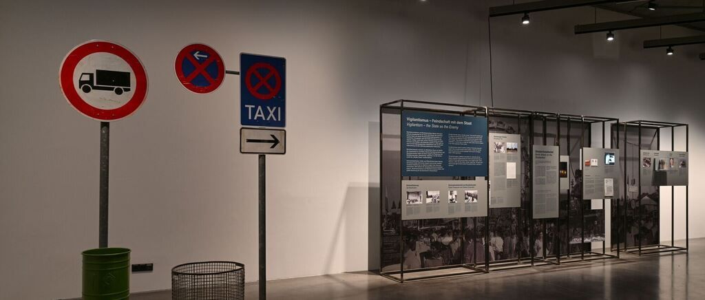 A museum exhibit with a taxi sign, a no-truck sign, and informational panels.