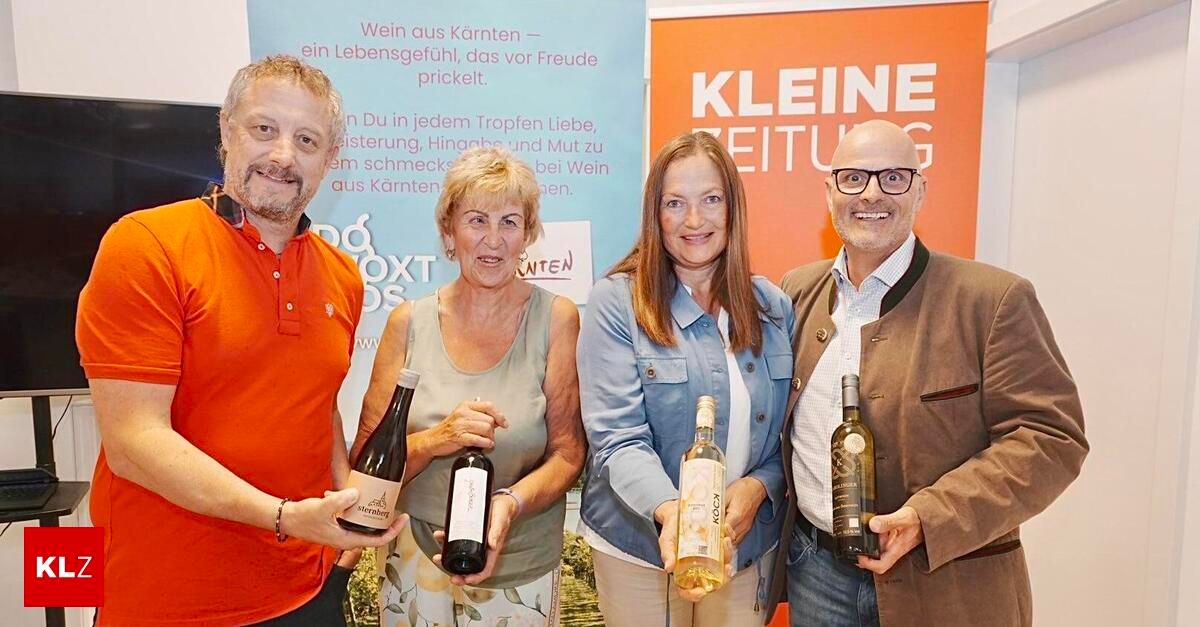 Vier Personen posieren mit Weinflaschen vor einem Hintergrund, auf dem 'kleine Zeitung' in weißen Großbuchstaben steht.