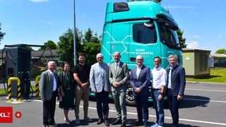 A group of people in formal wear pose for a photo in front of a Heinz Schauperl logistics truck.