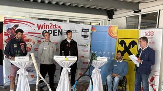Vier Männer bei einer Pressekonferenz mit Tennisausrüstung. Ein Mann im Rollstuhl hält ein Papier.