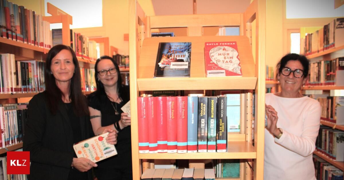 Two women stand in a bookstore, one holding a book. A wooden shelf displays several books, including 'Nur Ein Tag' and others.