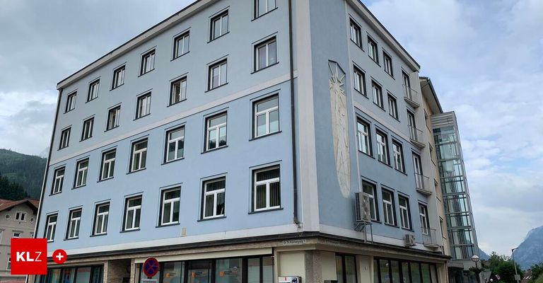 Ein blaues Gebäude mit mehreren Fenstern und einer dekorativen Wandmalerei. Auf der linken Seite des Gebäudes befindet sich ein Schild.