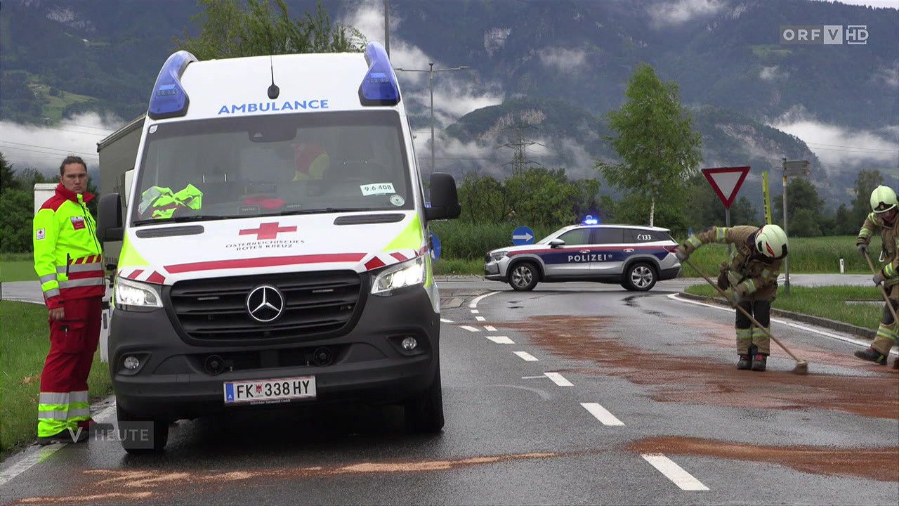 An ambulance with the plate FK 338 HY and police SUV are on a wet road with mountains in the background.