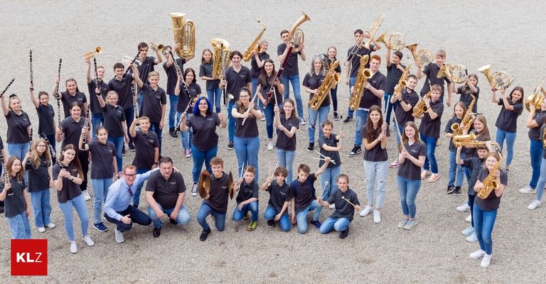 Eine große Gruppe junger Musiker posiert mit verschiedenen Instrumenten für ein Foto. Sie tragen alle passende schwarze Shirts.