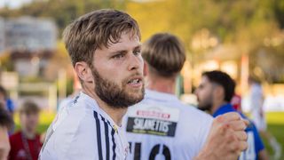 A man with a beard and mustache wearing a white shirt with the number 10.