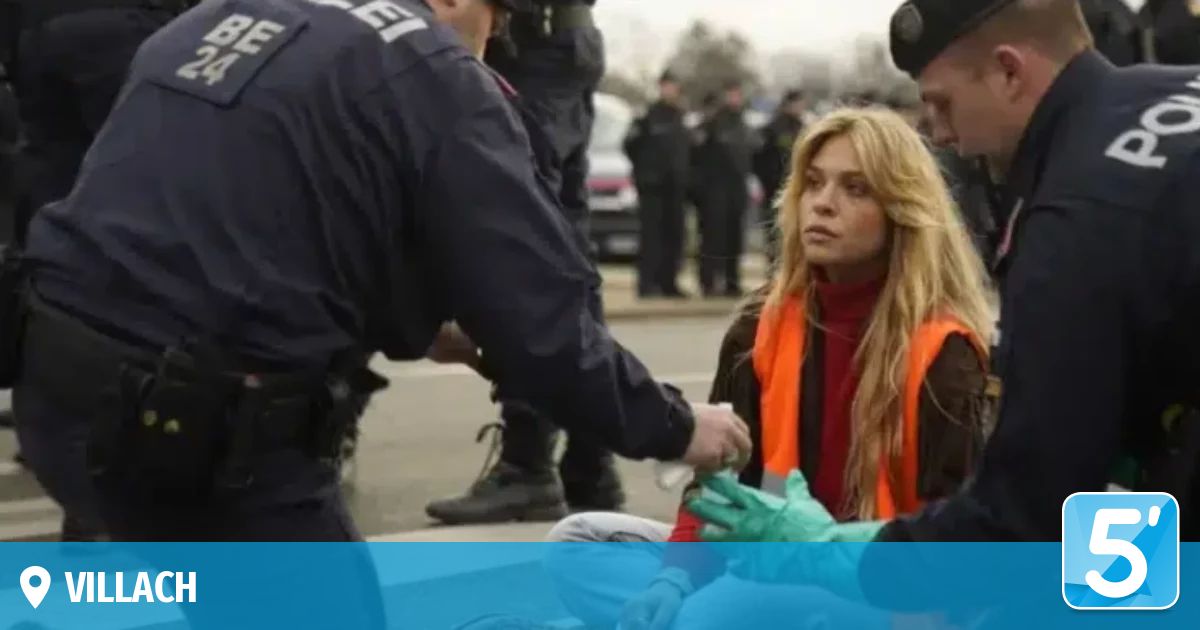 A police officer assists a woman in orange vest, while other officers stand behind them.