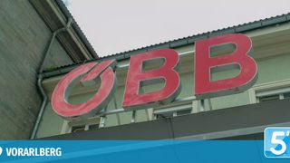 A red sign with the letters BB mounted on the side of a building under a clear sky.