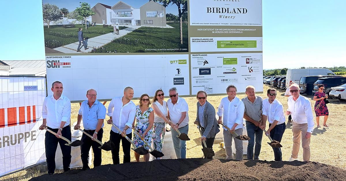 Eine Gruppe von Menschen bei einer Grundsteinlegung vor einem Baubanner mit Birdland Winery darauf.