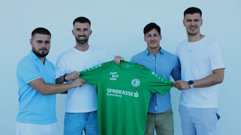 Vier Männer stehen zusammen vor einem weißen Hintergrund und halten ein grünes Shirt mit den Aufschriften Sport-Riss Jako und Sparkasse Korneuburg.