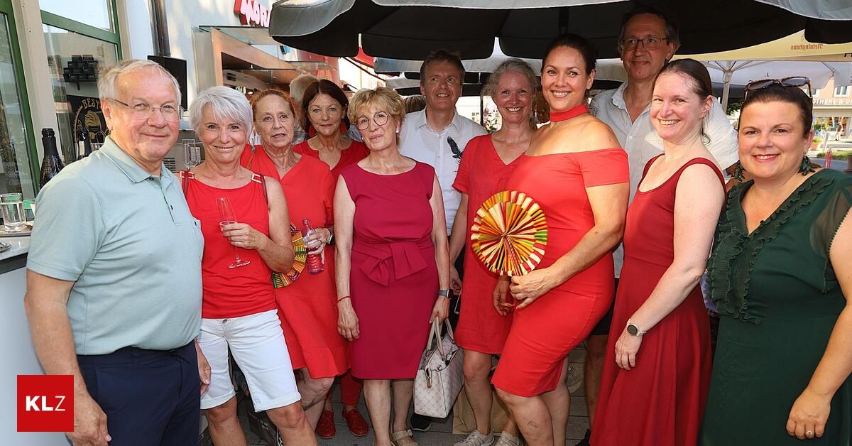 Eine Gruppe älterer Erwachsener in Rot steht draußen, lächelt und hält Getränke in der Hand, mit einem Mann in Blau und einer Frau, die einen bunten Fächer hält.