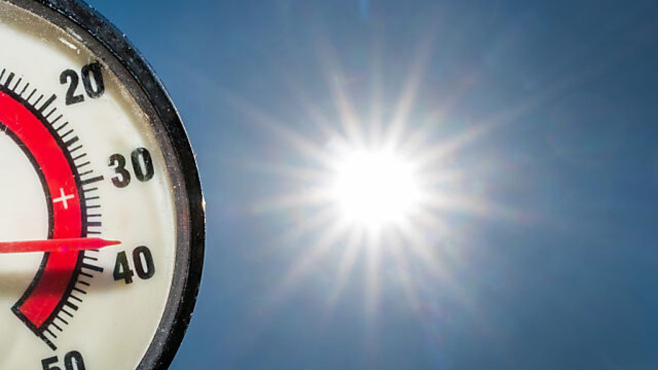 Ein Zifferblatt mit den Zahlen 0 und 12, vor einem hellblauen Himmel mit Sonne im Hintergrund.