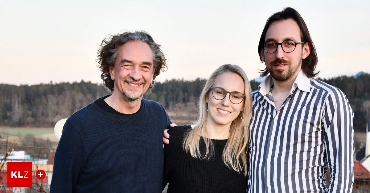 Drei Personen posieren lächelnd für ein Foto im Freien, mit einem Waldhintergrund. Ein Mann mit lockigem Haar, eine Frau mit Brille und ein weiterer Mann mit Bart und Brille.