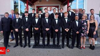 Eine Gruppe junger Männer in Anzügen und Fliegen, die auf den Stufen stehen, möglicherweise bei einer offiziellen Veranstaltung. Einige von ihnen lächeln und posieren für ein Foto.