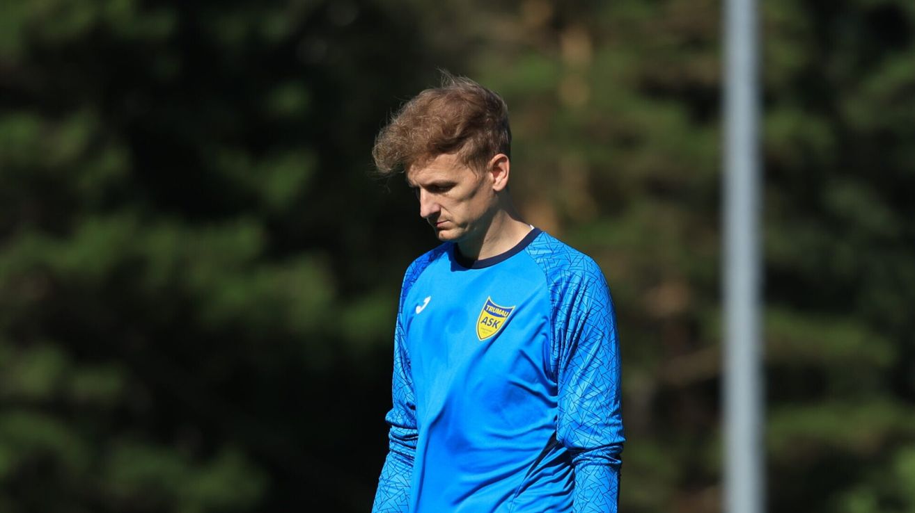Ein Fußballspieler in einem blauen Trikot mit gelben Akzenten steht auf dem Feld und schaut nach links.