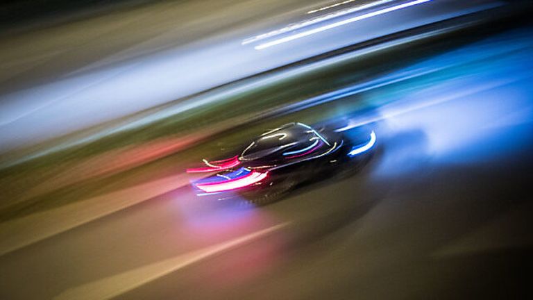 Eine unscharfe Aufnahme eines Autos mit roten, blauen und weißen Lichtern, das nachts auf einer Straße fährt.