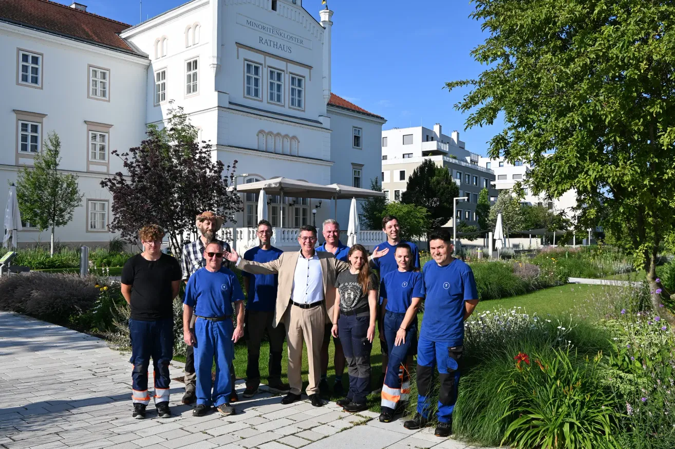 Eine Gruppe von Menschen in blauen Uniformen und einem Mann in Anzug posiert vor einem weissen Gebäude mit der Aufschrift Rathaus.