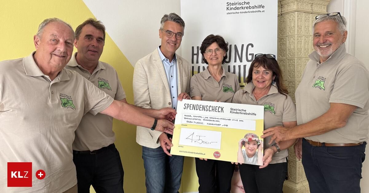 Eine Gruppe von Menschen, die einen Spendenscheck mit der Aufschrift 'Spendenscheck' vor einem Banner mit einem Bild eines Kindes halten.