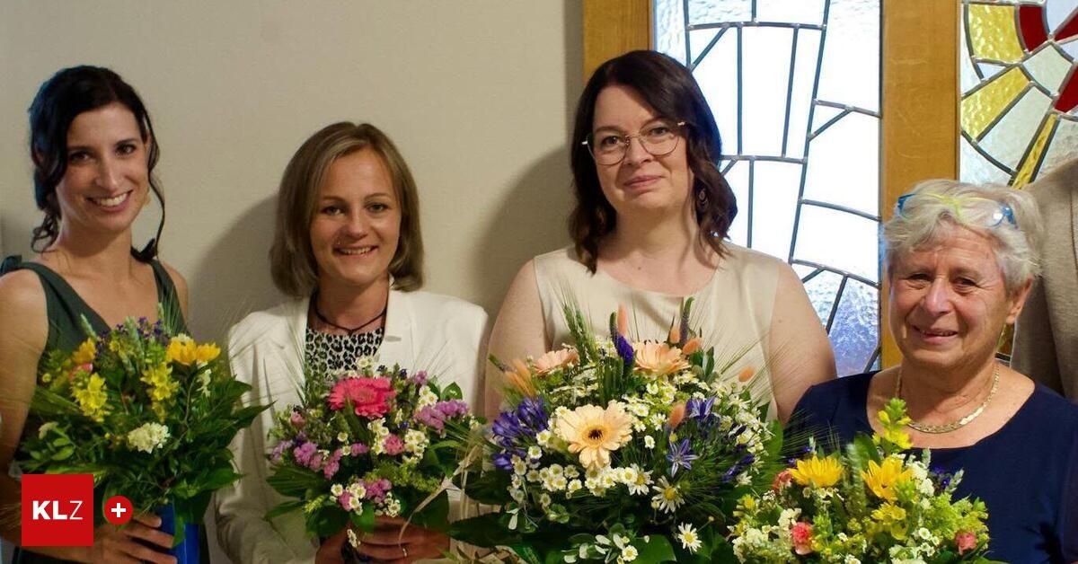 Drei Frauen halten Blumensträuße vor einem Buntglasfenster, wobei eine Frau lächelt und eine andere eine Brille trägt.