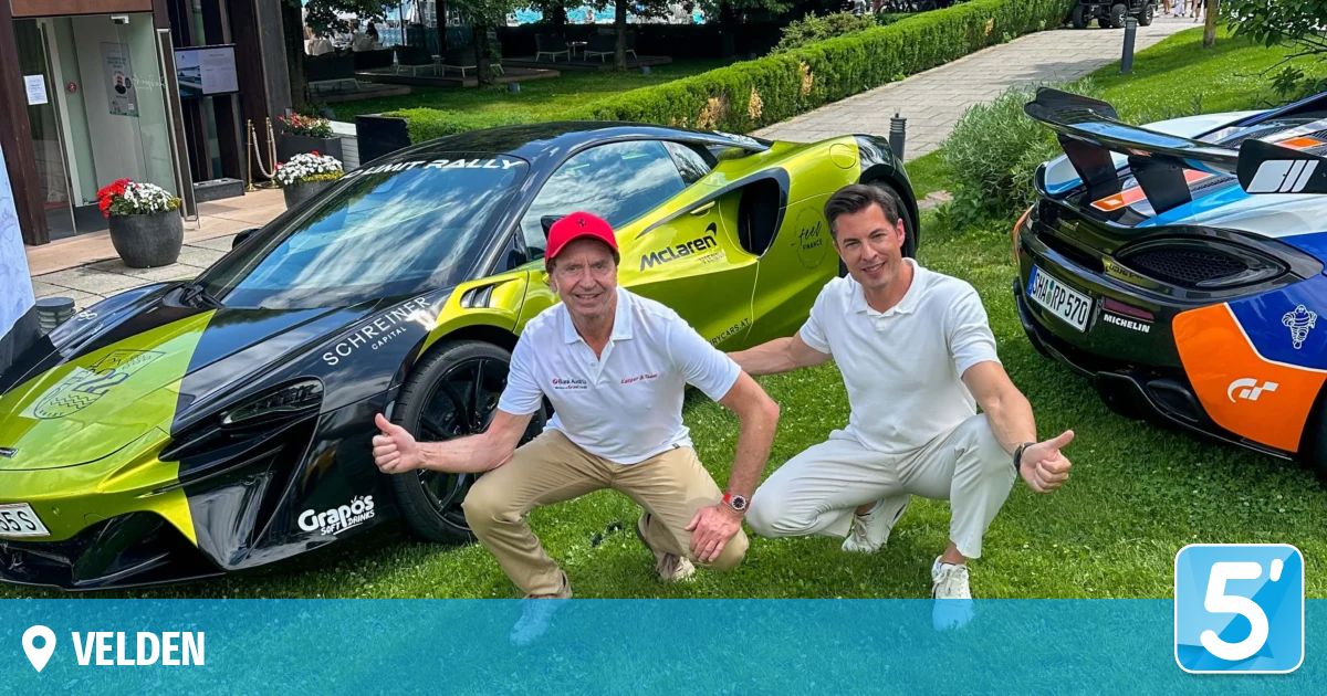 Zwei Männer posieren neben einem McLaren-Sportwagen auf einem Rasen. Der Mann auf der linken Seite trägt eine rote Kappe und ein weißes Hemd. Das Auto hat Sponsorenlogos.