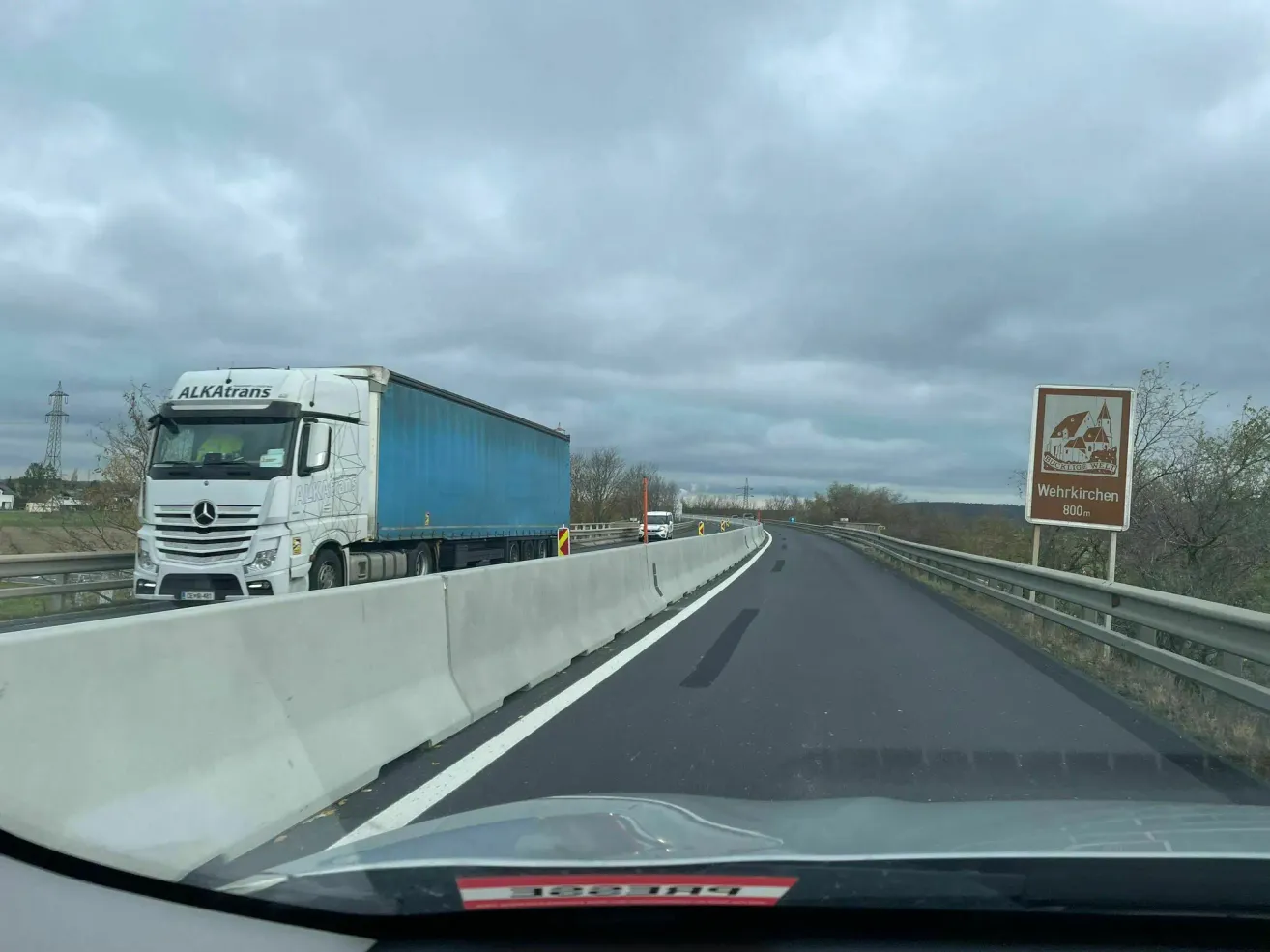 Eine Autobahn mit einem Lastwagen und einem Schild. Der Himmel ist bewölkt.