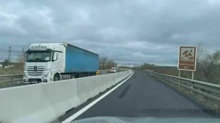 Eine Autobahn mit einem Lastwagen und einem Schild. Der Himmel ist bewölkt.
