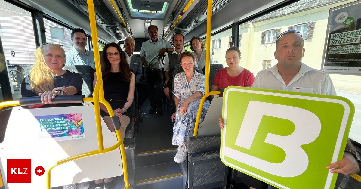 Eine Gruppe von Menschen sitzt lächelnd in einem Bus und schaut zur Kamera. Einige halten ein Buch.