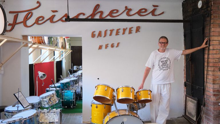 Ein Mann steht vor einem Schlagzeug in Gasteyer NFGs, einem Vintage-Drum-Studio, mit Trommeln und Becken im Hintergrund.
