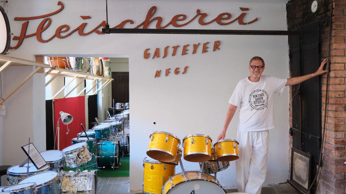 Ein Mann steht vor einem Schlagzeug in Gasteyer NFGs, einem Vintage-Drum-Studio, mit Trommeln und Becken im Hintergrund.