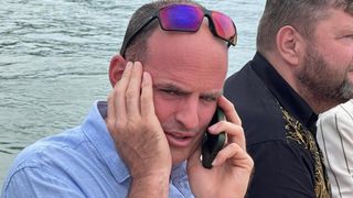 Ein Mann mit Sonnenbrille auf dem Kopf spricht mit einem Handy in beiden Händen.