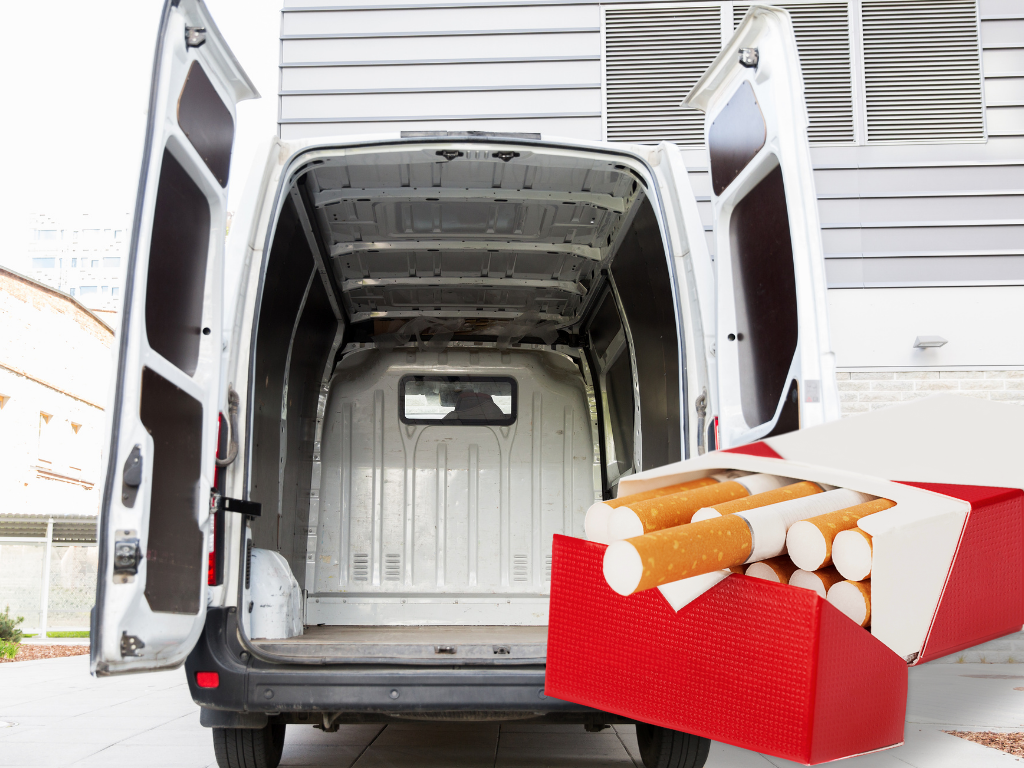 An open delivery van with a red box containing cigarettes placed on its side. The van is parked in front of a building.