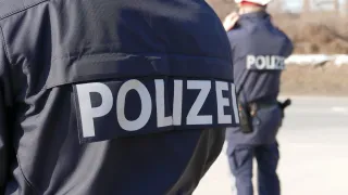 Ein Polizist steht mit einem anderen Beamten. Beide haben das Wort Polizei auf ihren Uniformen.