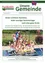 Eine Gruppe von Kindern und einer Frau befindet sich in einem Schwimmbecken. Die Frau lächelt und hebt ihre Hände. Die Kinder heben ebenfalls ihre Hände und scheinen sich zu amüsieren. Es gibt ein Metallgeländer an der Seite des Beckens. Der Hintergrund ist unscharf, mit einem Zaun und einigen Pflanzen.