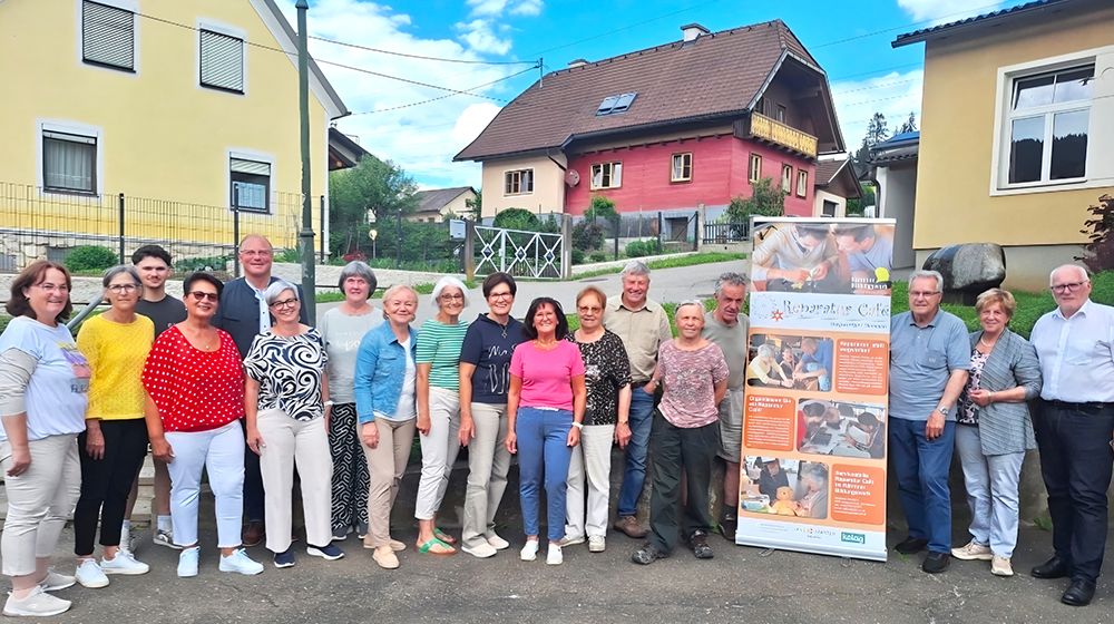 A group of people, both men and women, are posing for a photo in front of a colorful building with a banner.