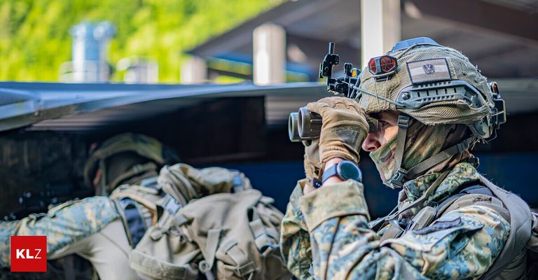 A soldier in camouflage uniform with a helmet and binoculars is looking through the scope, possibly on a mission.