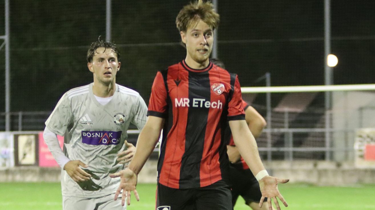 Two soccer players on a field, one in a red and black striped shirt with MR ETech, the other in a white shirt with a logo.