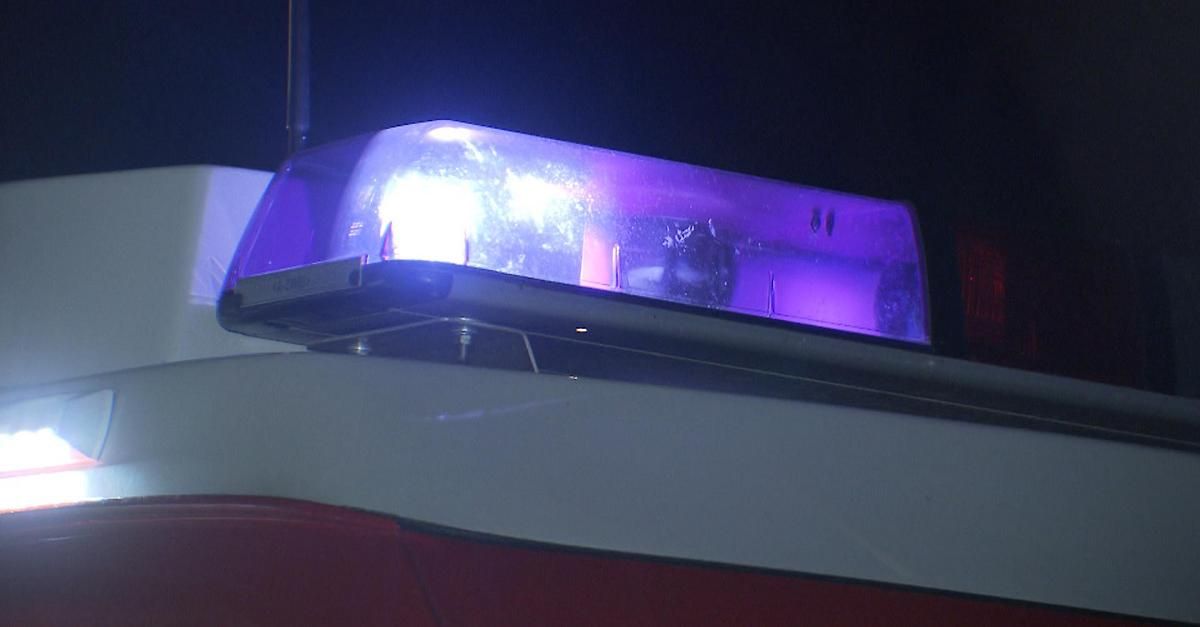 A close-up view of a police vehicle's roof with a purple light bar illuminated at night.