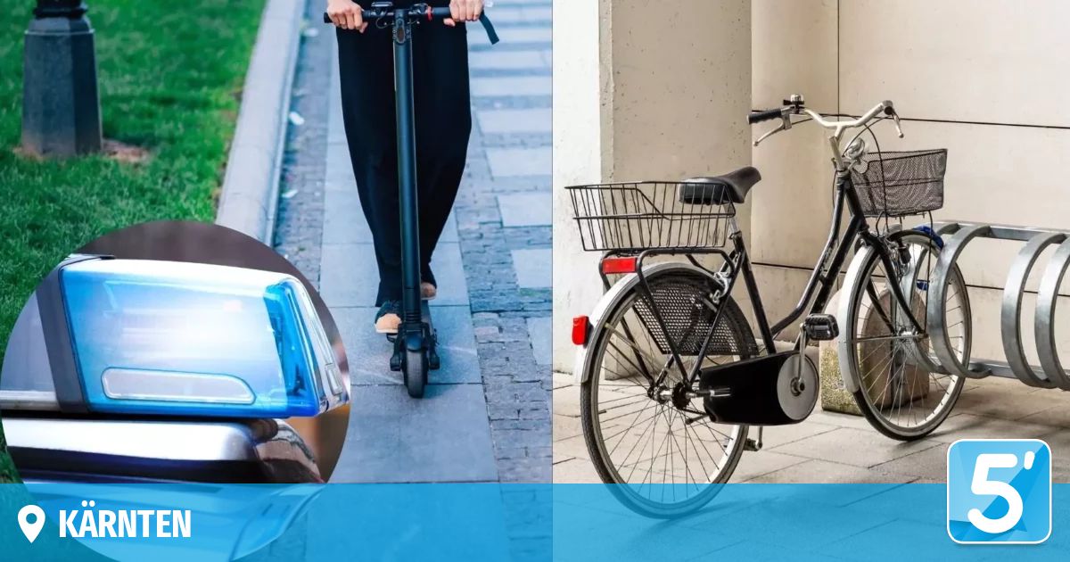 A person rides a black electric scooter on a brick sidewalk next to a building. A black bicycle with a basket is parked nearby.