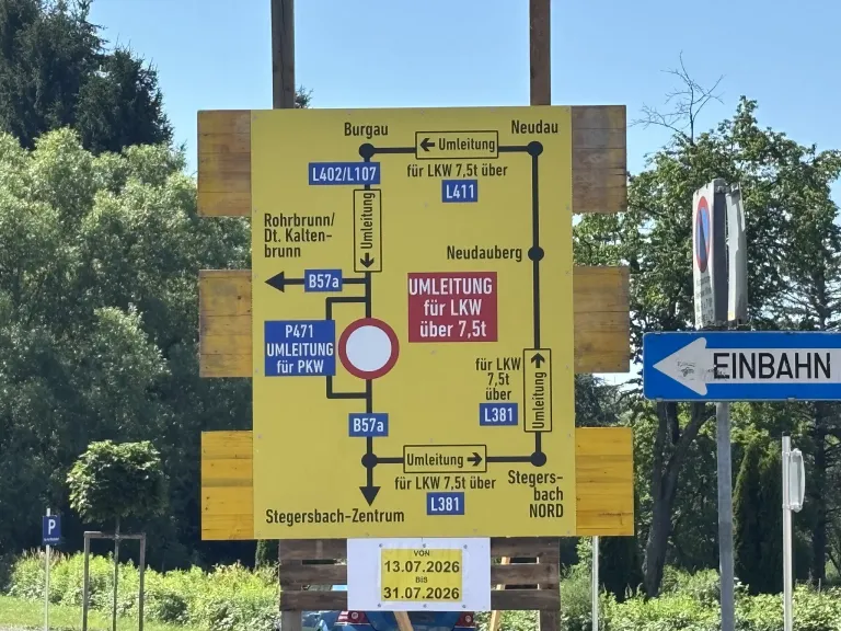 Ein gelbes Schild mit Wegbeschreibungen und Umleitungen für LKW und PKW, mit Daten vom 13.07.2026 bis 31.07.2026. Es enthält Routen wie Burgau, Neudau, Rohrbrunn und Stegersbach-Zentrum.