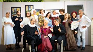 Eine Gruppe von Menschen in historischen Kostümen, wahrscheinlich Schauspieler, posiert für ein Foto auf einer Bühne.
