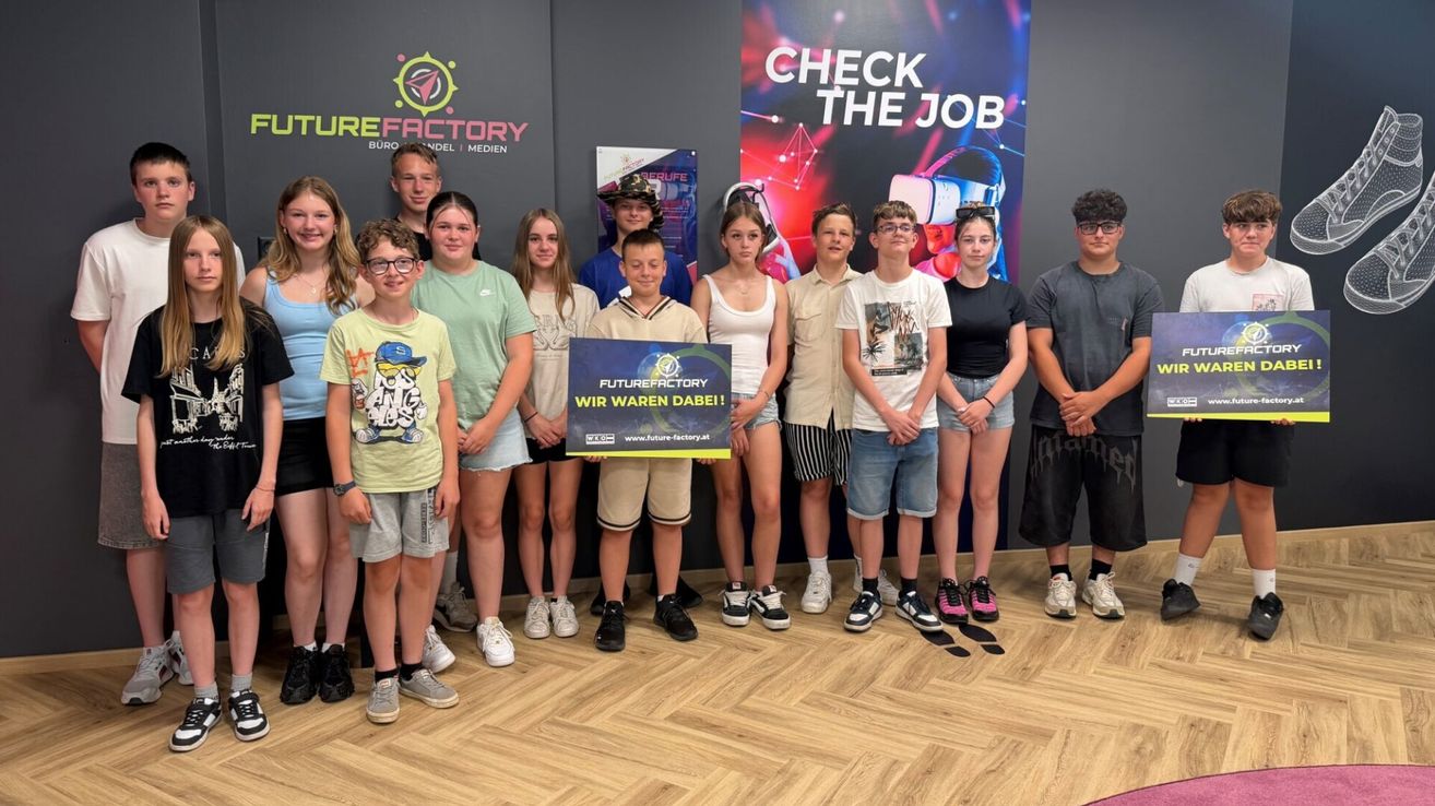 Eine Gruppe von Kindern und Jugendlichen steht zusammen für ein Foto in einem Raum mit einem Banner, das 'Check the Job' sagt. Sie halten ein Schild, auf dem 'Future Factory wir waren dabei!' steht.