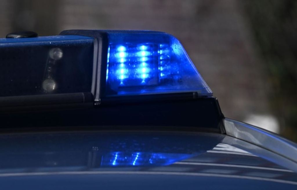 Nahaufnahme der blauen Warnleuchten eines Polizeiwagens, die auf einem dunklen Hintergrund blinken.