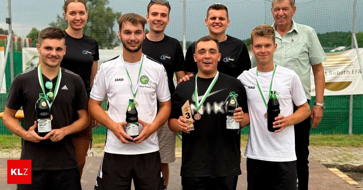 A group of young athletes, both male and female, are posing for a photo with their medals and drinks. They are all wearing sports uniforms.