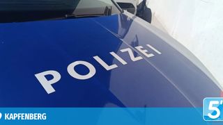 A close-up view of a blue police car with the word 'POLIZEI' written in white on the hood. The hood is slightly curved, and the car's front bumper is visible.