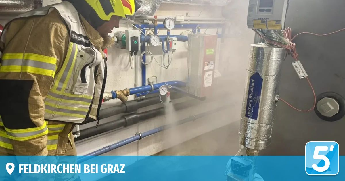 A firefighter in full gear is using a device to spray water in a room with industrial equipment and pipes. The room has a blue background with the text 'HEN BEI GRAZ'.