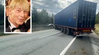 A man with blonde hair and a bow tie smiles at the camera. Beside him is a blue truck on the side of the road.