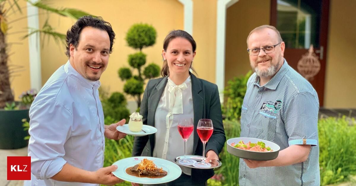Three people are posing for a photo while holding plates of food and wine glasses. The man on the left is holding a plate with a dessert, the woman in the middle is holding a plate with a dish and two wine glasses, and the man on the right is holding a bowl with a dish. They are all smiling and seem to be posing for a photo.