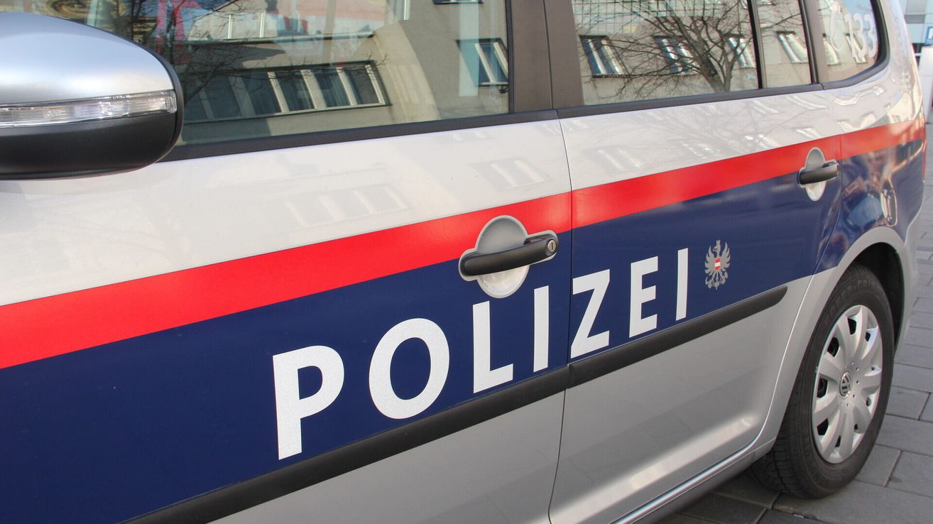 Eine Nahaufnahme der Tür eines Polizeiwagens mit dem Wort 'POLIZEI' in Weiß auf blauem Hintergrund. Der Türgriff ist silber.