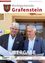 Zwei Männer stehen vor einem Gebäude mit dem Wort 'Grafenstein' über ihnen. Der Mann auf der linken Seite hält ein Stück Papier und lächelt. Der Mann auf der rechten Seite trägt ein Mikrofon. Hinter ihnen befindet sich ein Schild, das 'Marktgemeinderat Grafenstein' besagt.